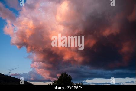 Dramatic pink orange grey storm clouds cell, brightly back lit from the sun shining Stock Photo
