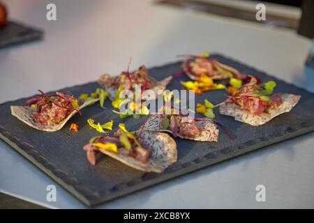 Closeup of gourmet appetizers on a slate plate with flowers and herbs, displaying culinary elegance Stock Photo