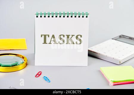Goals achievement and business success. TASK word in a notebook next to a magnifying glass, calculator, stickers and paper clips on a gray background Stock Photo