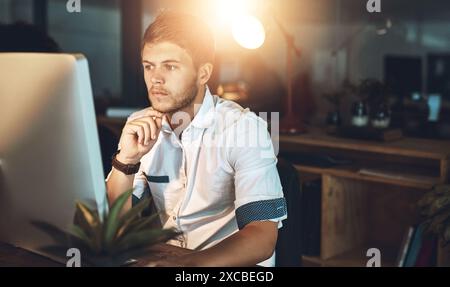 Computer, thinking and businessman in office at night with research for coding on website with deadline. Planning, ideas and male software developer Stock Photo