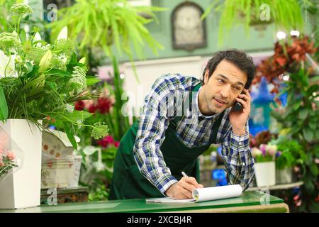 Florist in flower shop taking an order from a customer on the phone Stock Photo