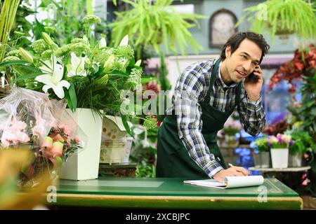 Florist in flower shop taking an order from a customer on the phone Stock Photo