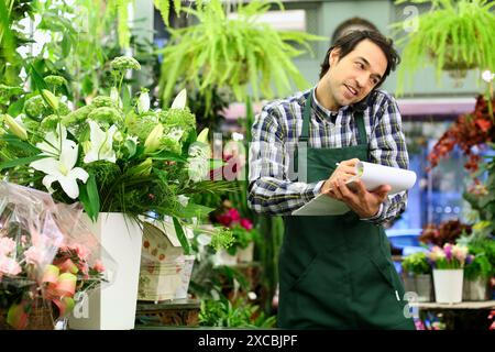 Florist in flower shop taking an order from a customer on the phone Stock Photo