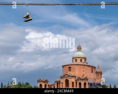 A pair of sports shoes hang from electrical cables, with the sanctuary of San Luca, Bologna, Italy in the background Stock Photo