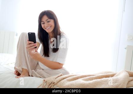 Woman using smartphone and smiling Stock Photo