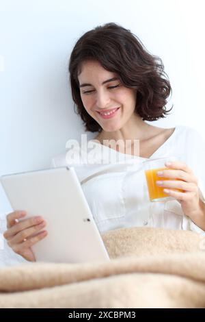 Woman using digital tablet and holding a glass of juice Stock Photo