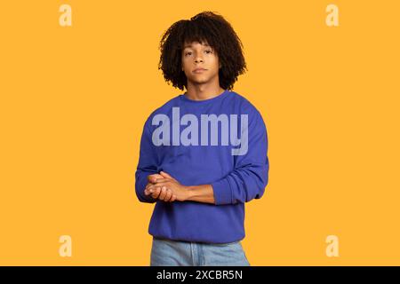 Handsome Young Man Wearing Blue Sweatshirt Against Yellow Background Stock Photo