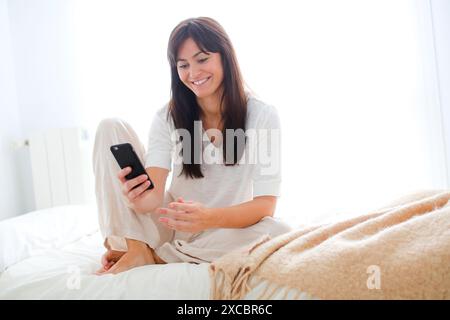 Woman using smartphone and smiling Stock Photo