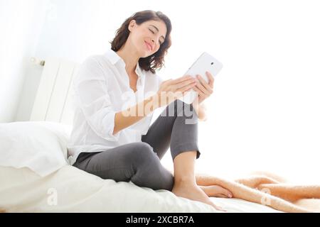 Woman using tablet computer and smiling Stock Photo