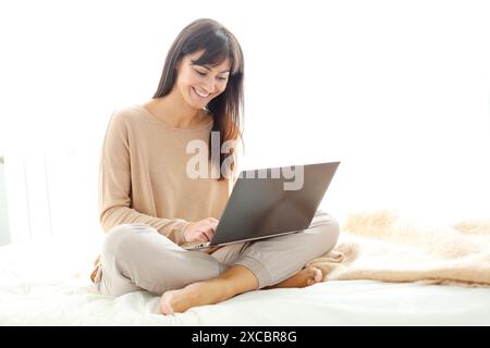 Woman using laptop computer and smiling Stock Photo