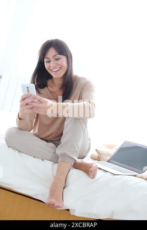 Woman using smartphone and smiling Stock Photo