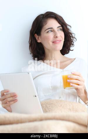Woman using digital tablet and holding a glass of juice Stock Photo