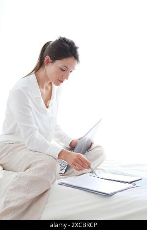 Woman sitting on bed and using  laptop Stock Photo