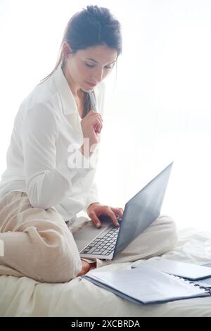 Woman sitting on bed and using  laptop Stock Photo