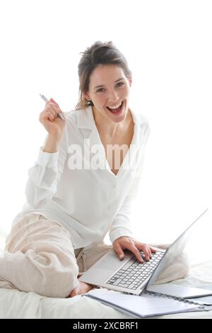 Woman sitting on bed and using  laptop Stock Photo