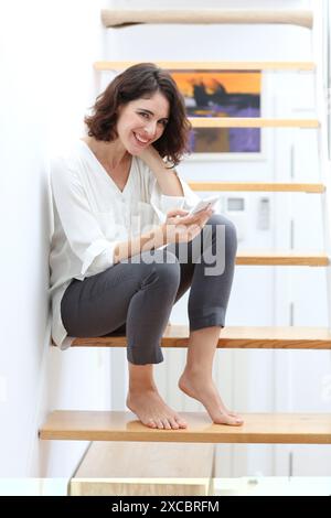 Woman sitting on stairs and using smart phone Stock Photo