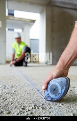 Workers with personal protective equipment, PPE, Marking guide lines for the construction of interior walls, Line tracer, housing construction, concre Stock Photo