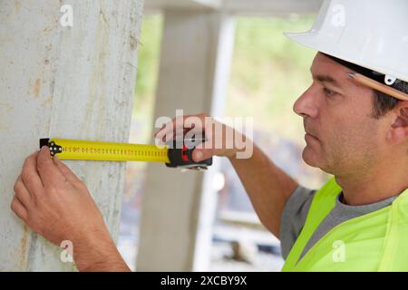 Worker with protective equipment, PPE, Taking measures in concrete beam, retractable tape, housing construction, Basque Country, Spain Stock Photo