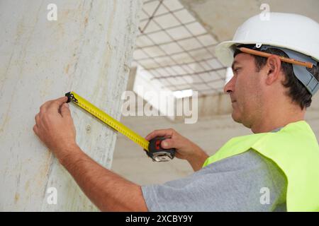 Worker with protective equipment, PPE, Taking measures in concrete beam, retractable tape, housing construction, Basque Country, Spain Stock Photo