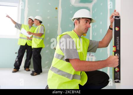 Worker with protective equipment, PPE, Leveling plasterboard panels, housing construction, level, Basque Country, Spain Stock Photo