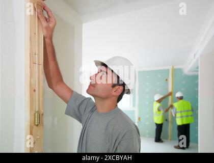Worker with protective equipment, PPE, Checking and aligning vertical sections in preframe door, housing construction, Plumb line, Basque Country, Spa Stock Photo