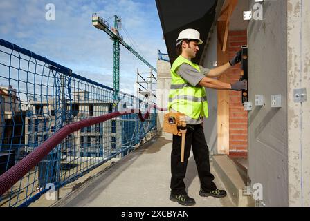 Mason checking the level of a wall, Bricklayer with personal protective equipment, PPE, Apartment Building under construction, Donostia, San Sebastian Stock Photo