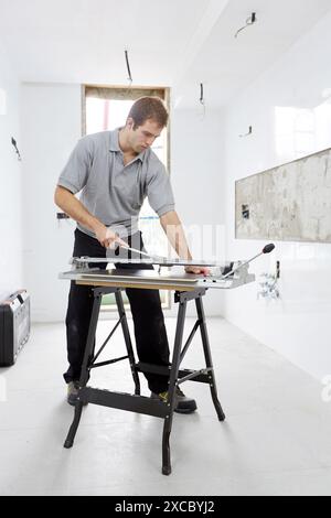 Bricklayer cutting tile. Manual tile cutter. Construction Industry. Stock Photo