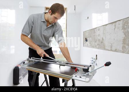 Bricklayer cutting tile. Manual tile cutter. Construction Industry. Stock Photo