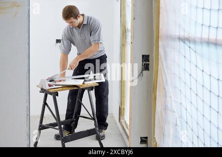 Bricklayer cutting tile. Manual tile cutter. Construction Industry. Stock Photo