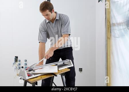 Bricklayer cutting tile. Manual tile cutter. Construction Industry. Stock Photo