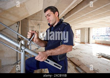 Worker using pliers, new homes under construction, construction site Stock Photo