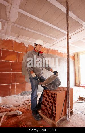 Bricklayer with trowel, bricks, new homes under construction, construction site Stock Photo