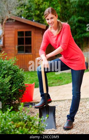 Woman leaning on shovel in garden center Stock Photo - Alamy