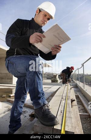 Construction workers measuring, personal protective equipment, housing construction Stock Photo