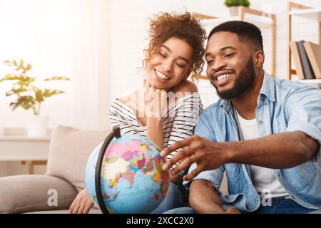 Man and Woman Sitting on Couch Looking at a Globe Stock Photo
