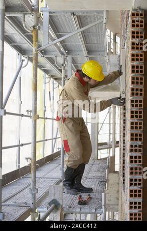 Worker with spirit level on scaffold, housing construction. Guipuzcoa, Euskadi, Spain Stock Photo