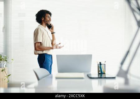 Businessman walking in his office and talking on phone Stock Photo