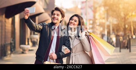 Young couple taking selfie near boutiques outdoors Stock Photo