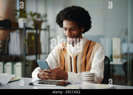 Smiling engineer answering text messages from client Stock Photo