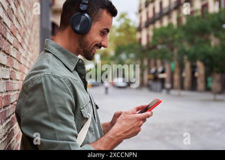 Handsome man relaxing outdoors using phone and listening music in a city street. Stock Photo