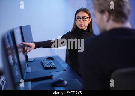 Cybersecurity professionals discussing and analyzing network security data on multiple screens in office Stock Photo
