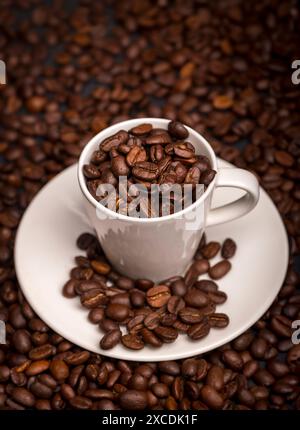 Espresso cup filled with roasted coffee beans, coffee bean background. Stock Photo