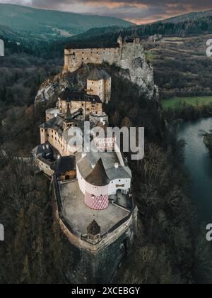 Aerial drone view of Oravsky hrad monument in Slovakia. Night scenic overhead view of medieval Hungarian fortress on high rock above Orava river, ancient historical stone walls and castle towers Stock Photo