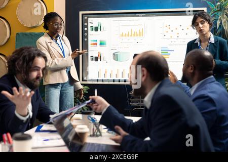 Team of enterprise workers preparing their pitch for the stakeholders meeting, working on ways to obtain more capital. Employees attend a conference to address financial potential. Stock Photo
