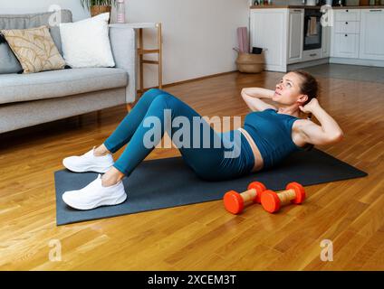 Woman in sportswear doing abs exercise at home. Ab workout. Stock Photo