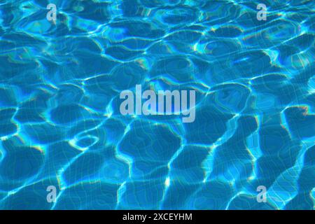 Concept - summer, leisure, lifestyle. Swimming pool surface with light ripple patterns and reflections. Blue ceramic tiled floor. Stock Photo