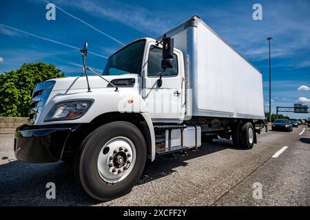 Industrial carrier middle duty white day cab rig semi truck with long box trailer for local freights transporting commercial cargo running on the wide Stock Photo