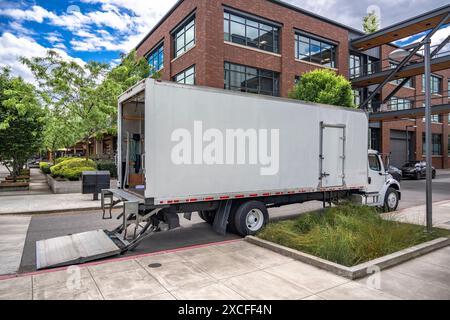 Industrial carrier middle duty day cab rig semi truck with box trailer for local freights standing with open back door on the urban city street making Stock Photo