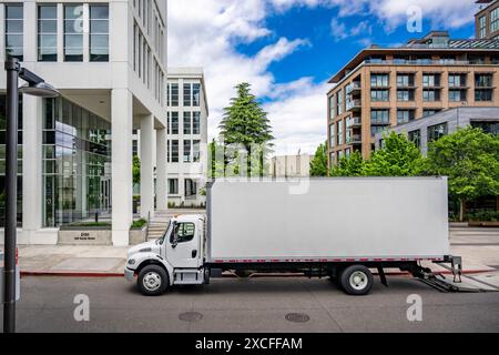 Industrial carrier middle duty day cab rig semi truck with box trailer for local freights standing with open back door on the urban city street making Stock Photo