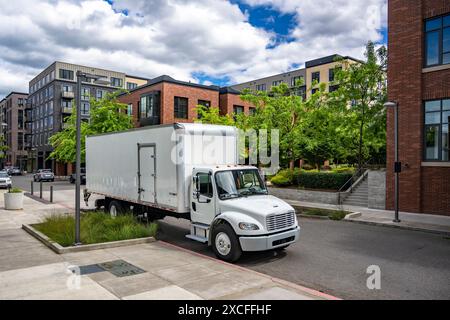 Industrial carrier middle duty day cab rig semi truck with box trailer for local freights standing with open back door on the urban city street making Stock Photo